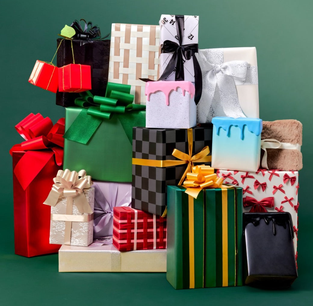 A pile of wrapped holiday gifts on a green backdrop